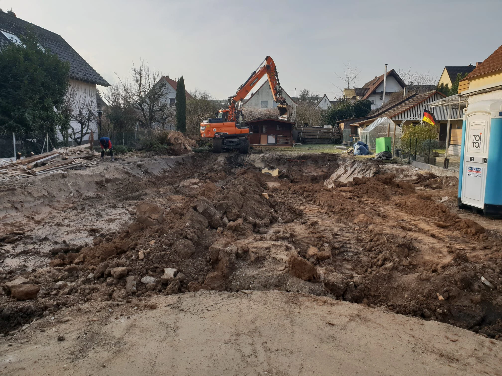Bagger und ausgehobene Baugrube auf Grundstück für Erdarbeiten vor Hausbau