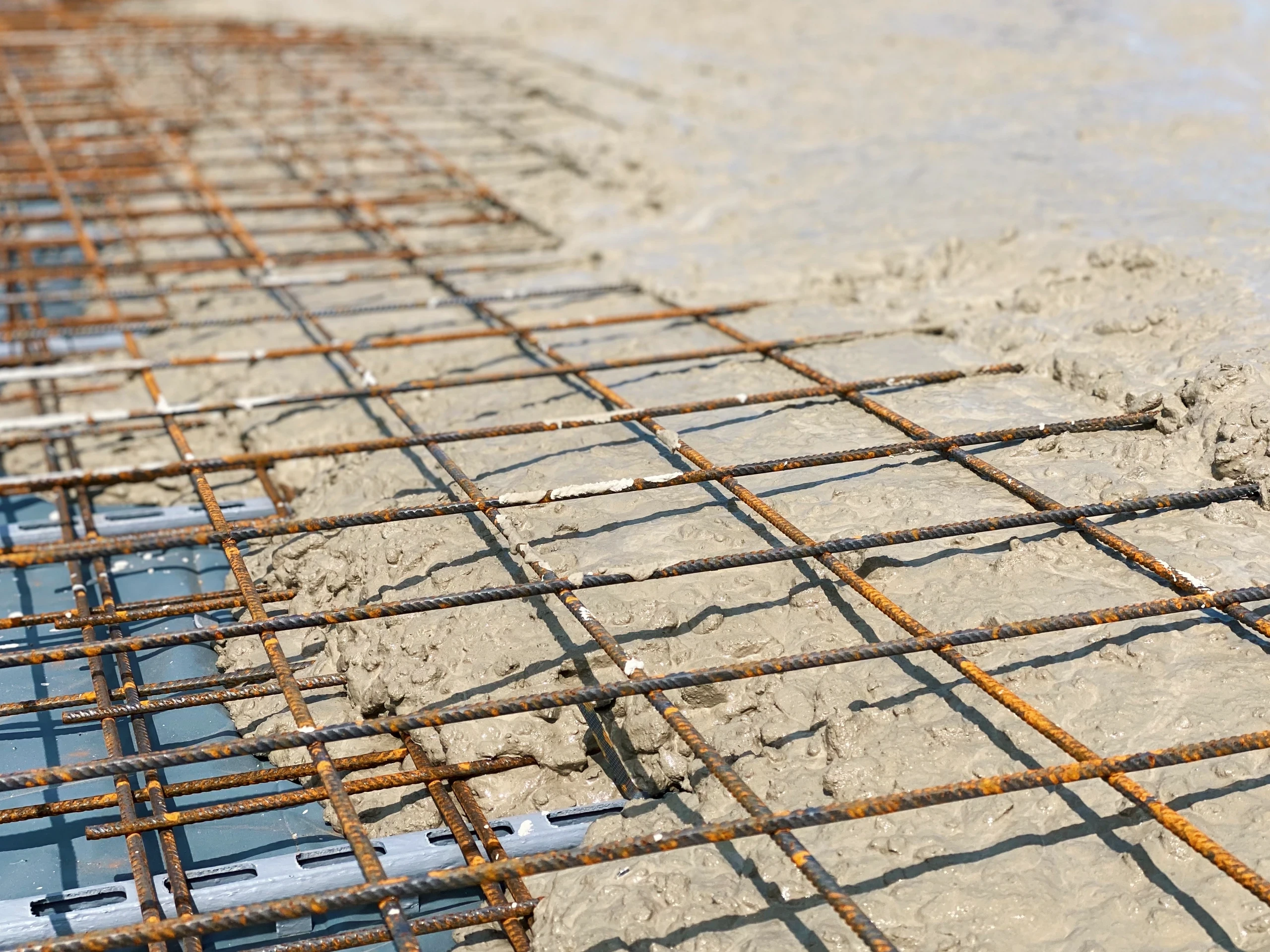 Bewehrtes Stahlgitter für die Bodenplatte wird mit frischem Beton ausgegossen