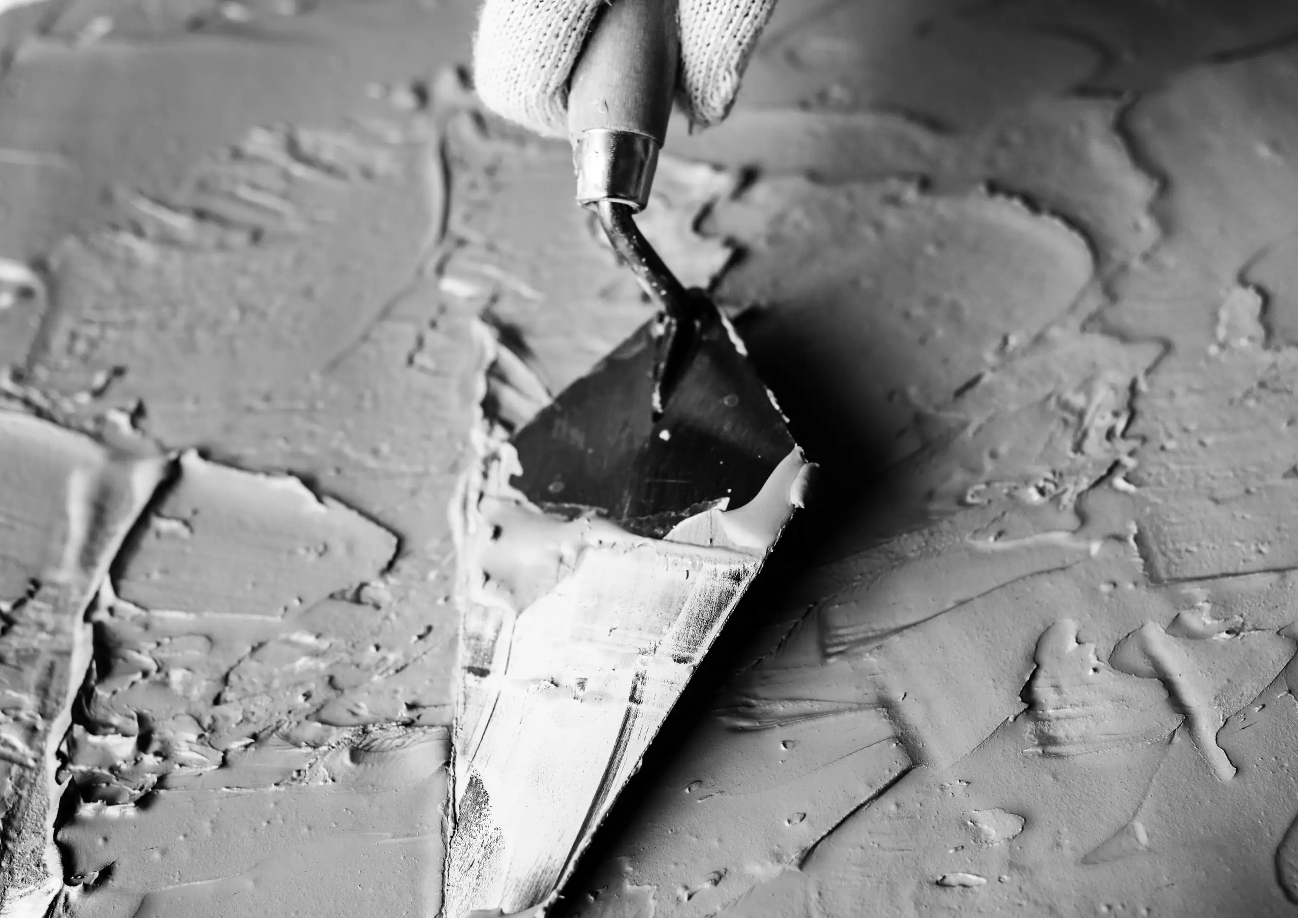 Nahaufnahme einer Glättkelle, die Putz auf einer Wandfläche verteilt – Putzarbeiten