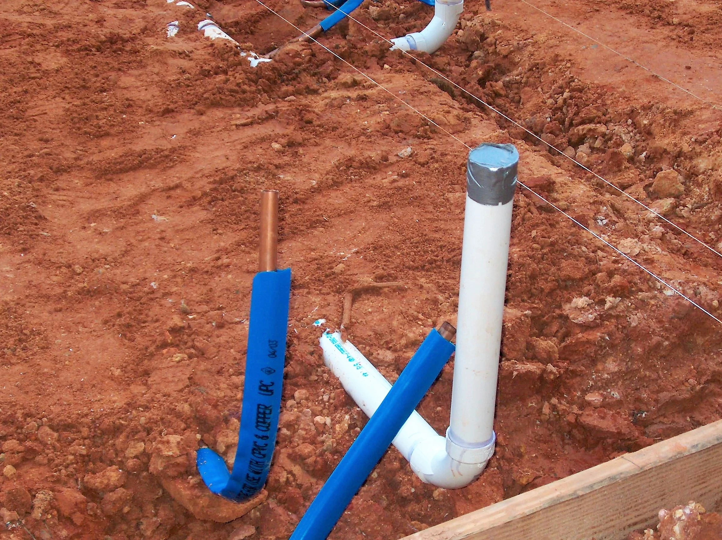 Freigelegte Abwasser- und Versorgungsrohre im Aushub für Erdarbeiten