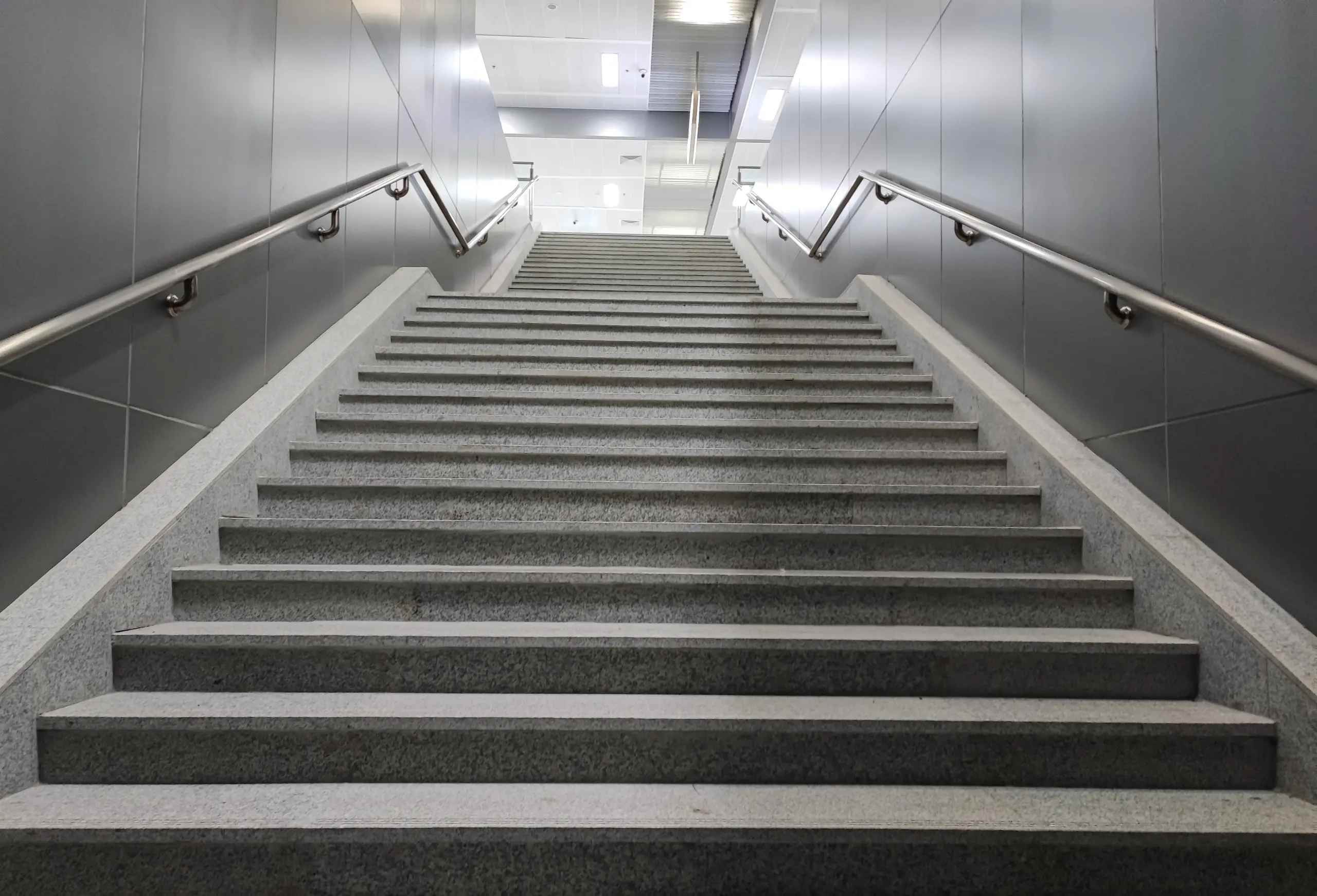 Betontreppe in hellem Innenbereich mit Edelstahl-Handläufen