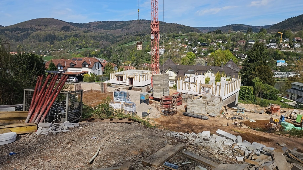 Rohbau eines Wohnhauses am Hang mit Kran und Schalungsarbeiten im Vordergrund